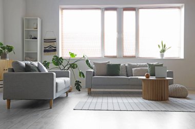 Koltukları ve çiçekleri olan aydınlık oturma odasının içinde.