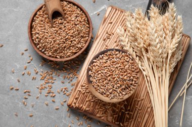 Tahta kaseler, tahıllar, buğday kulakları ve grunge gri arka planda yiyecek.