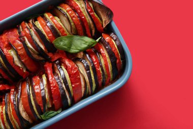 Kırmızı arka planda lezzetli Ratatouille yemeği.