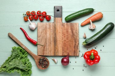 Yeşil ahşap mutfak masasında taze sebzeli tahta kesme tahtası.