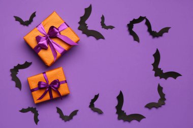 Cadılar Bayramı partisi için kağıt yarasalardan yapılmış çerçeve ve mor arka planda hediye kutuları