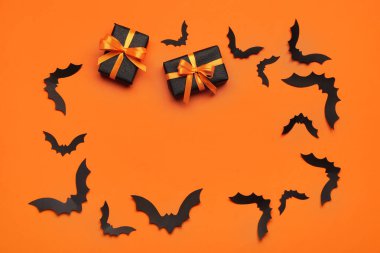 Cadılar Bayramı partisi için kağıt yarasalardan yapılmış çerçeve ve turuncu arka planda hediye kutuları