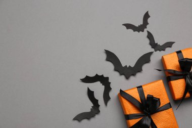Cadılar Bayramı partisi için kağıt yarasalar ve gri arka planda hediye kutuları.