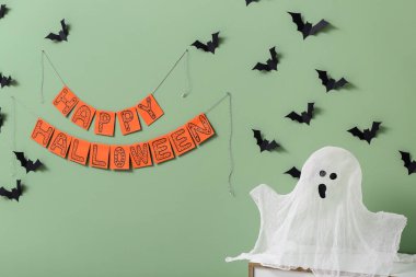 Cadılar Bayramı için dekore edilmiş yeşil duvarda hayalet ve kağıt yarasalarla dolu tuvalet.