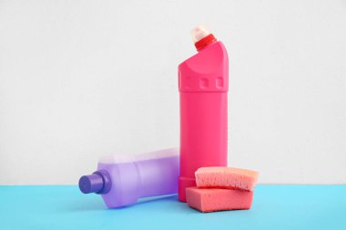 Mavi masada beyaz arka planda deterjan ve sünger şişeleri