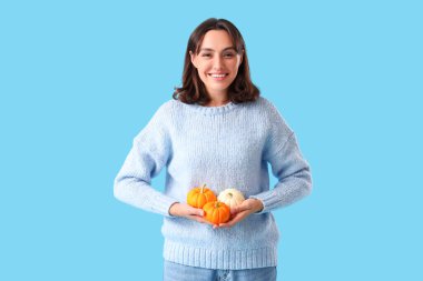 Mavi arka planda balkabağı olan genç bir kadın.