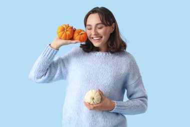 Mavi arka planda balkabağı olan genç bir kadın.