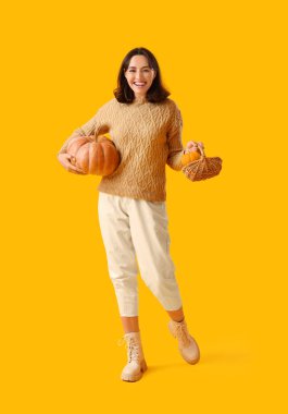 Sarı arka planda balkabağı olan genç bir kadın.