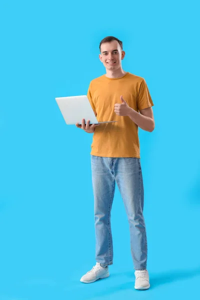 Mladý Muž Notebookem Ukazující Palec Nahoru Modrém Pozadí — Stock fotografie