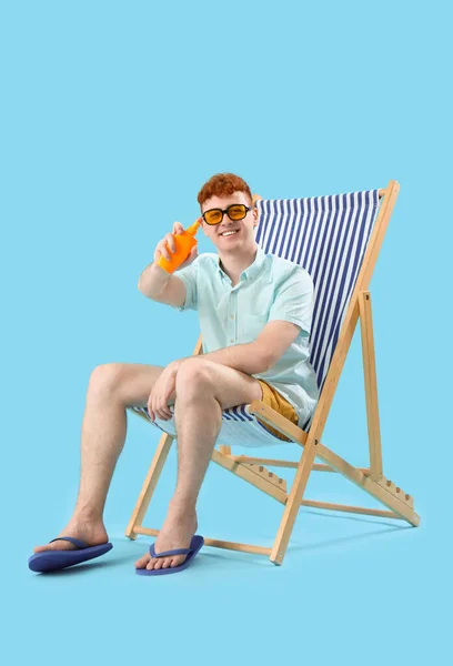 Junger Mann Mit Sonnencreme Liegestuhl Auf Blauem Hintergrund — Stockfoto