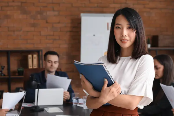 Female Asian business consultant with folder working in office