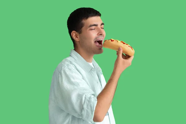 Молодой Человек Ест Вкусный Хот Дог Зеленом Фоне — стоковое фото