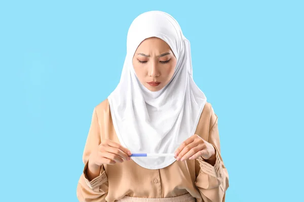 Besorgte Junge Asiatin Hijab Mit Schwangerschaftstest Auf Blauem Hintergrund — Stockfoto