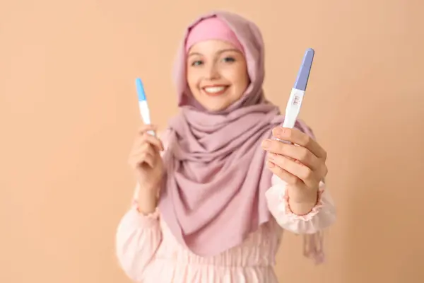 ベージュの背景で肯定的な妊娠テストを持つ幸せなムスリムの若い女性 — ストック写真