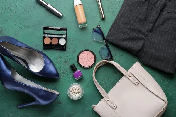 Composition with decorative cosmetics, accessories and clothes on green background