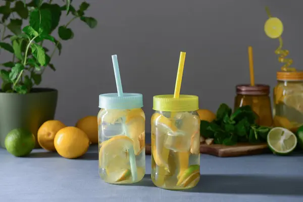 Mason jars of tasty lemonade with lime and mint on blue table