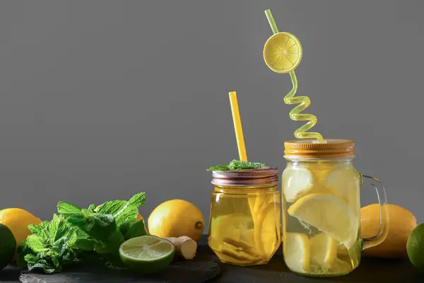 Mason jars of tasty lemonade with mint and lime on black table
