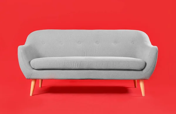 红色背景的舒适的灰色沙发 — 图库照片