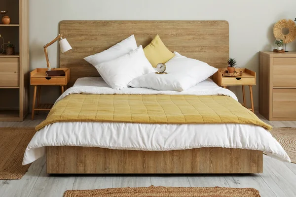 Interior of stylish bedroom with alarm clock on bed