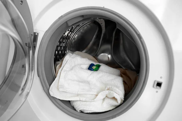Washing machine with laundry and capsule, closeup