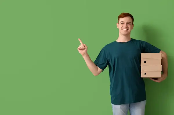 Szczęśliwy Młody Człowiek Kartonowymi Pudełkami Wskazujący Coś Zielonym Tle Wyprzedaż — Zdjęcie stockowe