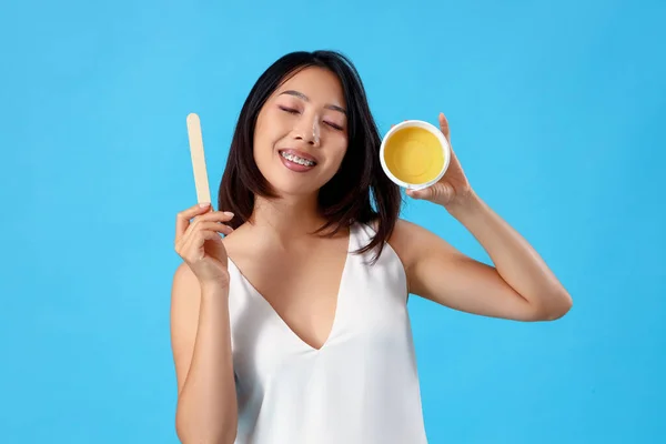 Young Asian woman with wax on blue background