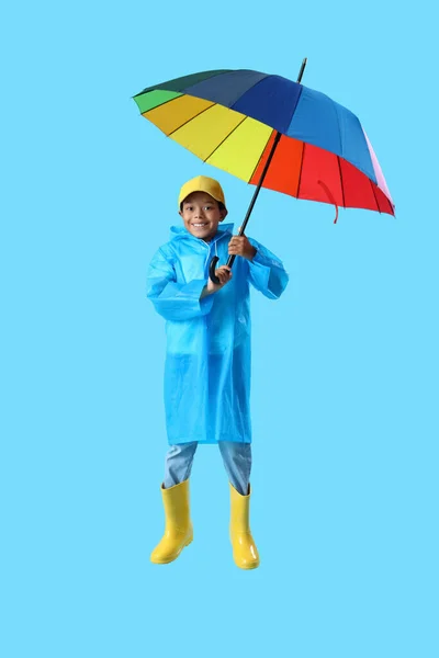 Afroamerikansk Liten Pojke Regnrock Med Paraply Hoppar Blå Bakgrund — Stockfoto