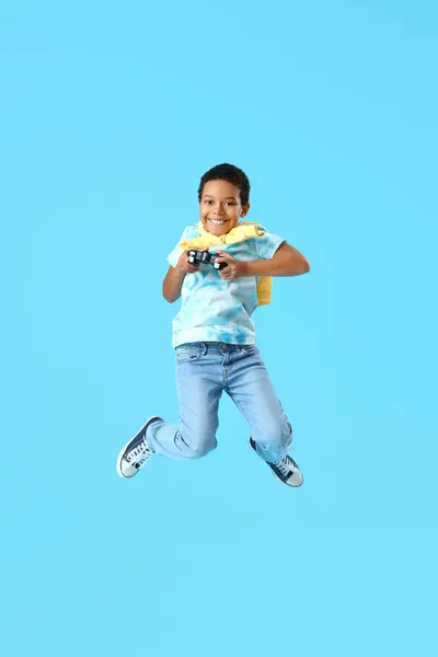 青い背景にジャンプゲームパッドを持つアフリカ系アメリカ人の少年 — ストック写真