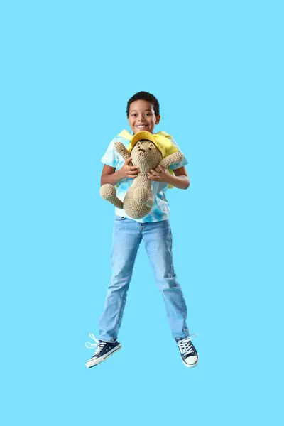 Menino Afro Americano Com Brinquedo Urso Saltando Fundo Azul — Fotografia de Stock