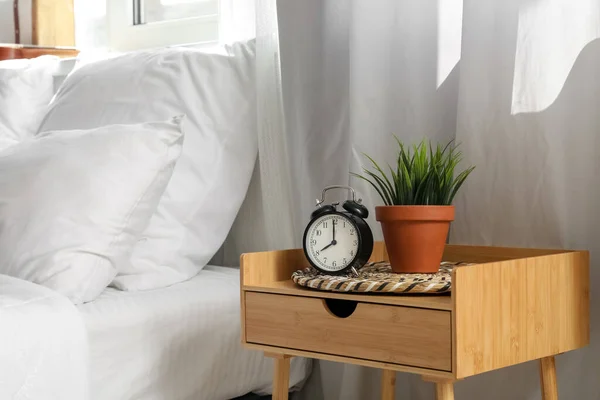 Alarm clock on bedside table in interior of bedroom
