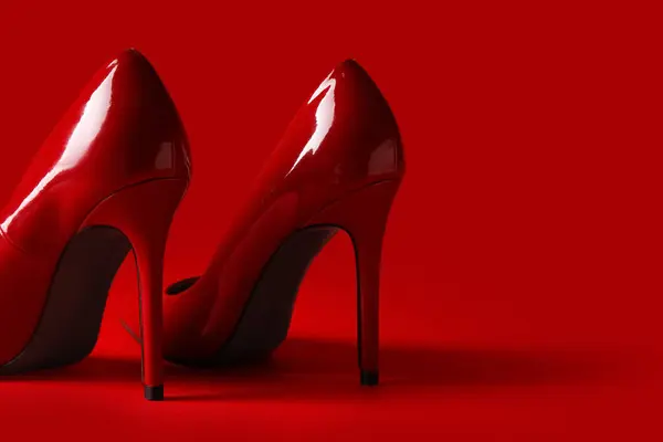 Stylish red high heels on color background