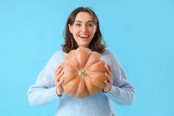 Young woman with pumpkin on blue background