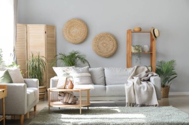 Koltukları, çiçekleri ve masası olan aydınlık oturma odasının içinde.