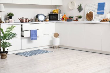 Modern mutfağın içinde şık halı, çöp kutusu ve beyaz tezgahlar var.