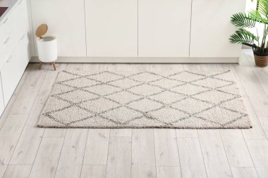 Modern mutfağın içinde şık halı, çöp kutusu ve beyaz tezgahlar var.