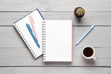 Kalemli defterler ve gri ahşap arka planda bir fincan lezzetli kahve.