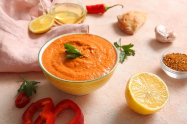 Bir kase lezzetli muhammara ve bej arka planda malzemeler.