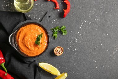 Bir kase lezzetli muhammara ve siyah arka planda malzemeler.
