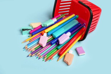 Kırmızı alışveriş sepeti ve mavi arka planda farklı okul kırtasiyesi.