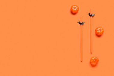 Turuncu arka planda Cadılar Bayramı kutlaması için kağıt dekorlu pipetler ve balkabakları içmek