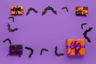 Cadılar Bayramı partisi için kağıt yarasalardan yapılmış çerçeve ve mor arka planda hediye kutuları