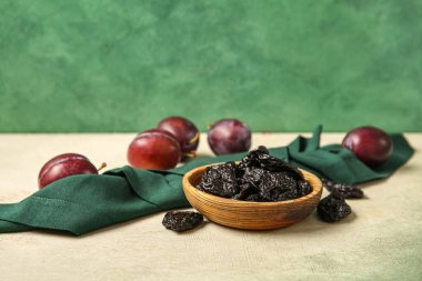 Lezzetli eriklerle dolu bir kase ve yeşil arka planda beyaz grunge masasında olgun erikler.