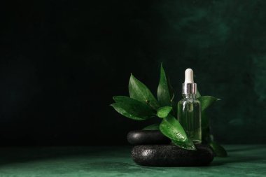 Yeşil arka planda gerekli yağ, spa taşları, dal ve çiçekli şişe