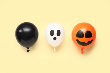 Sarı arka planda farklı komik Cadılar Bayramı balonları