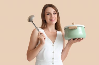 Bej arka planda tavuk çorbası ve kepçe pişiren genç bir kadın.