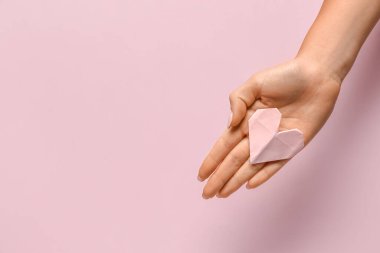 Pembe arka planda kağıttan yapılmış güzel bir kalbi olan kadın eli. Ulusal Tatlı Gün