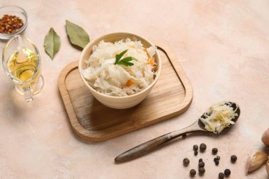 Bir kase lezzetli lahana turşusu ve pembe arka planda farklı baharatlar.