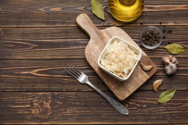 Lezzetli lahana turşusu ve ahşap arka planda farklı baharatlar.