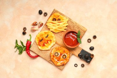 Farklı tatlı Cadılar Bayramı pizzaları ve pembe arka planda sos olan bir pano.