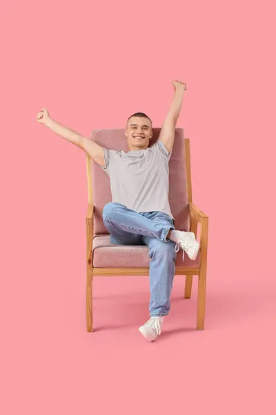 Szczęśliwy Młody Człowiek Siedzi Krześle Różowym Tle — Zdjęcie stockowe